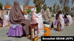 Əfqan qadınlar Qəndəharda Ramazan ayı zamanı xeyriyyə fondu tərəfindən paylanan ərzaq yardımını aldıqdan sonra oturublar.