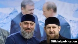 Adam Delimxanov (solda) və Ramzan Kadırov (Arxa planda Putinlə Axmad Kadırovun portreti) 