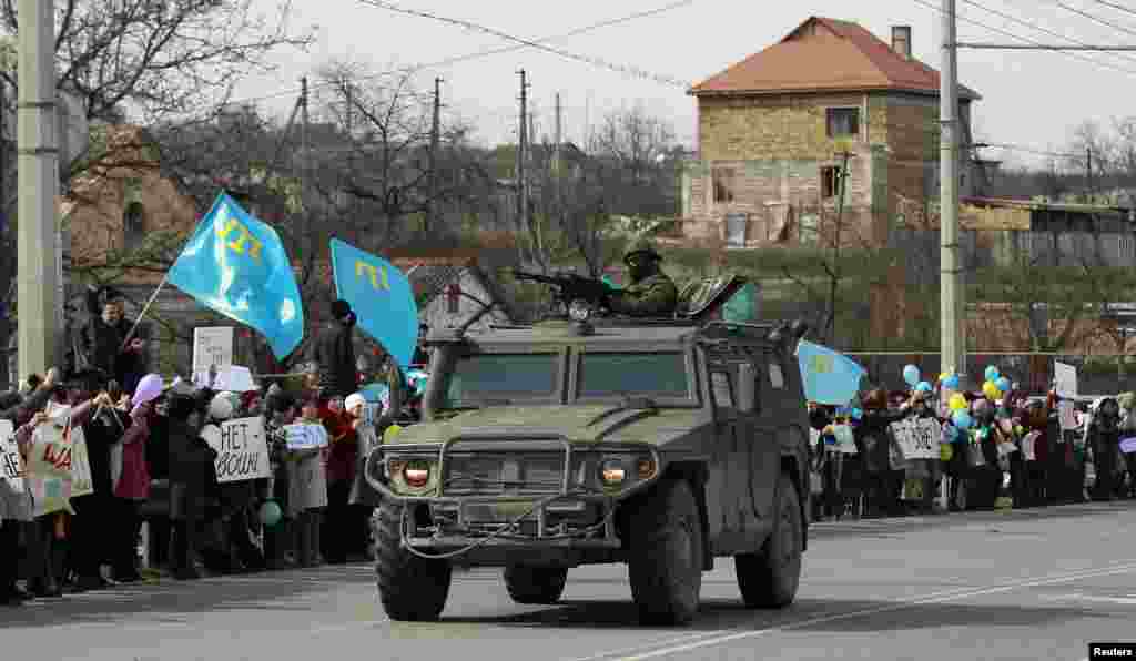 Simferopol yaxınlığında Krımın Ukrayna tərkibində qalmasını tələb edən qüvvələrin qarşısından keçən Rusiya ordusunun hərbi maşını